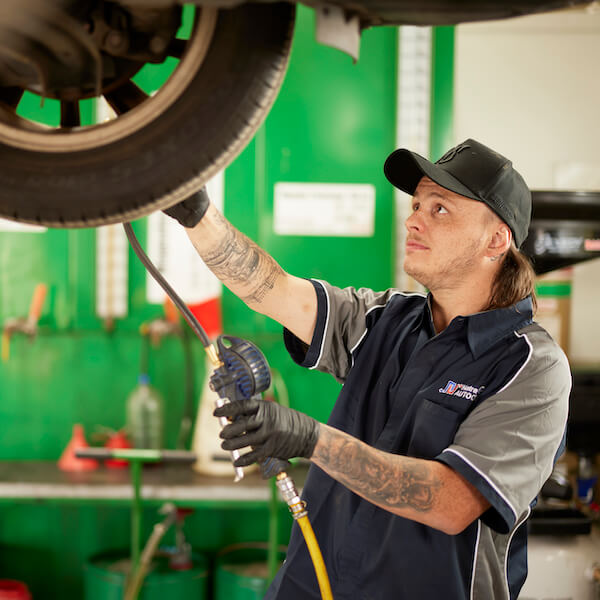 Auto mechanic checking tire pressure in green repair shop