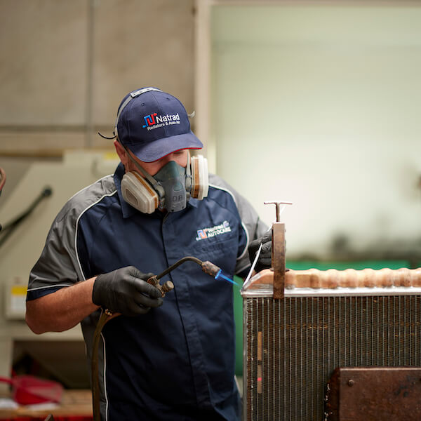 Worker wearing respirator mask welding industrial equipment in workshop