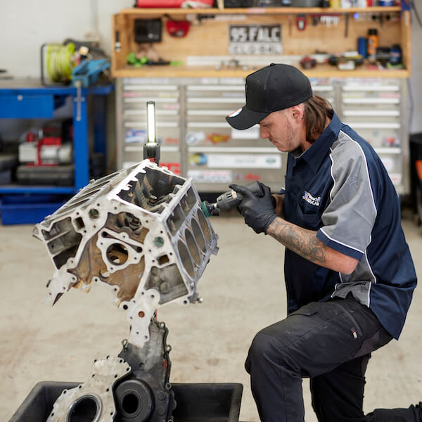 Mechanic working on large engine block in automotive workshop
