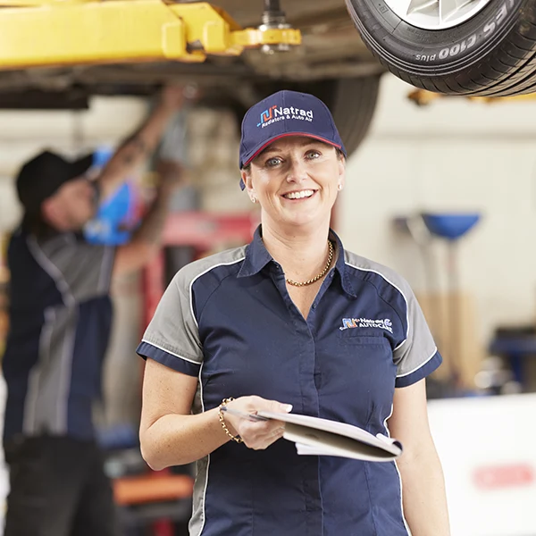 Smiling female automotive technician in Natrad uniform at service center
