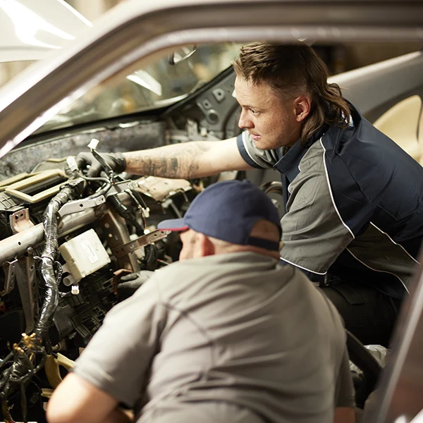 Mechanics working together to repair a car engine in an auto shop