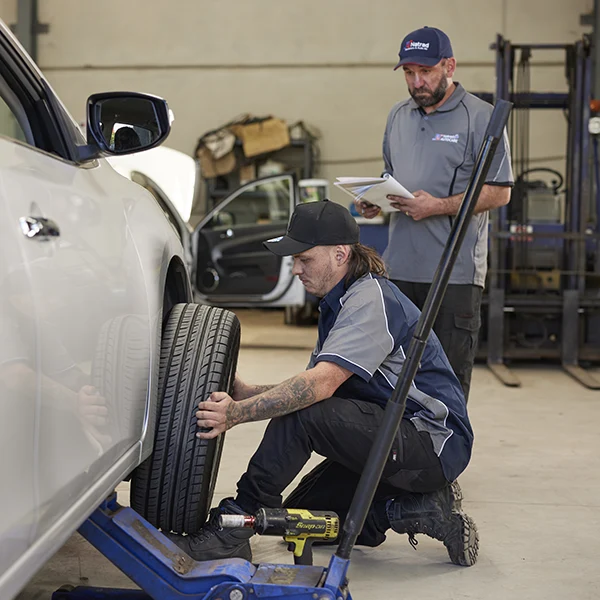 Auto mechanic checking tire on vehicle lift in repair shop