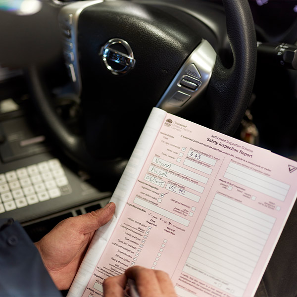 Hand holding safety inspection report inside Nissan vehicle