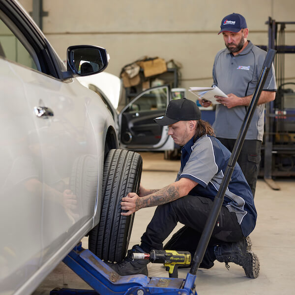 Mechanic checking tire on vehicle in automotive service center