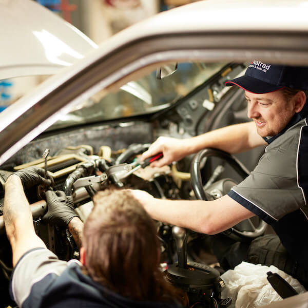 Mechanic working on car engine in auto repair shop