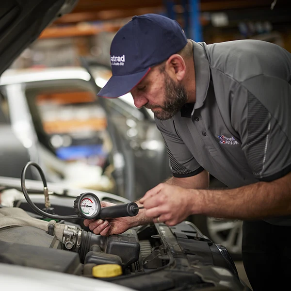 Mechanic checking car engine pressure with diagnostic tool