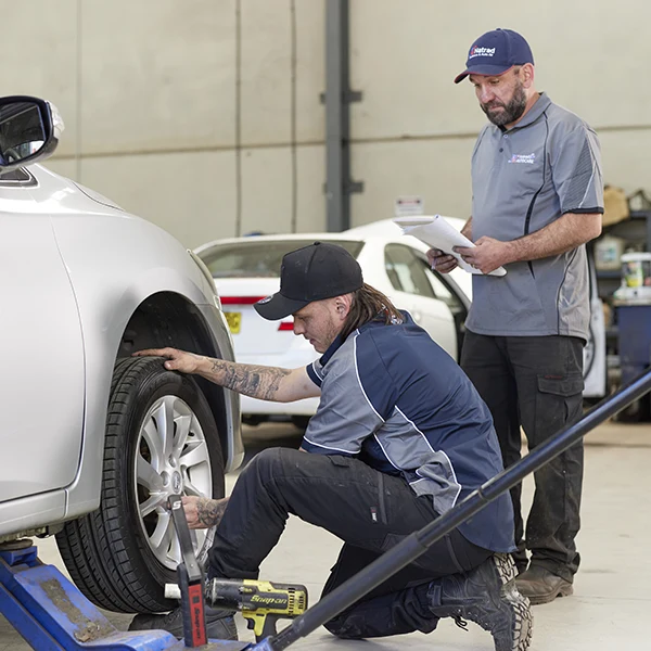 Mechanics working on a car tire in an auto repair shop
