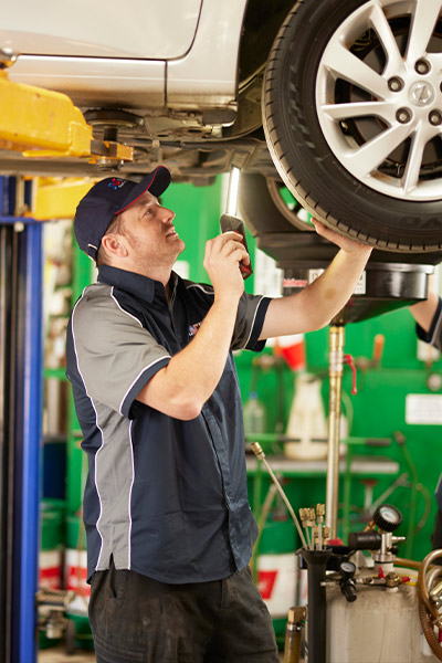Mechanic inspecting car tire on lift in automotive repair shop