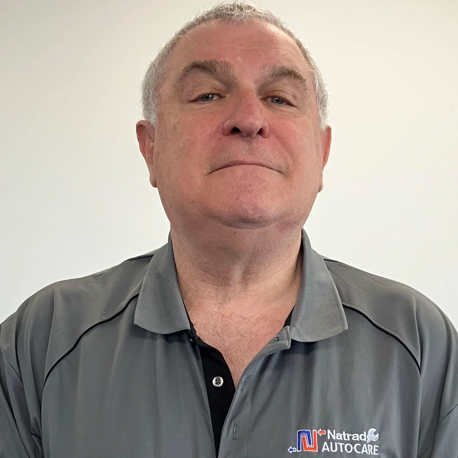 Mature man in gray Natrad Autocare polo shirt looking directly at camera