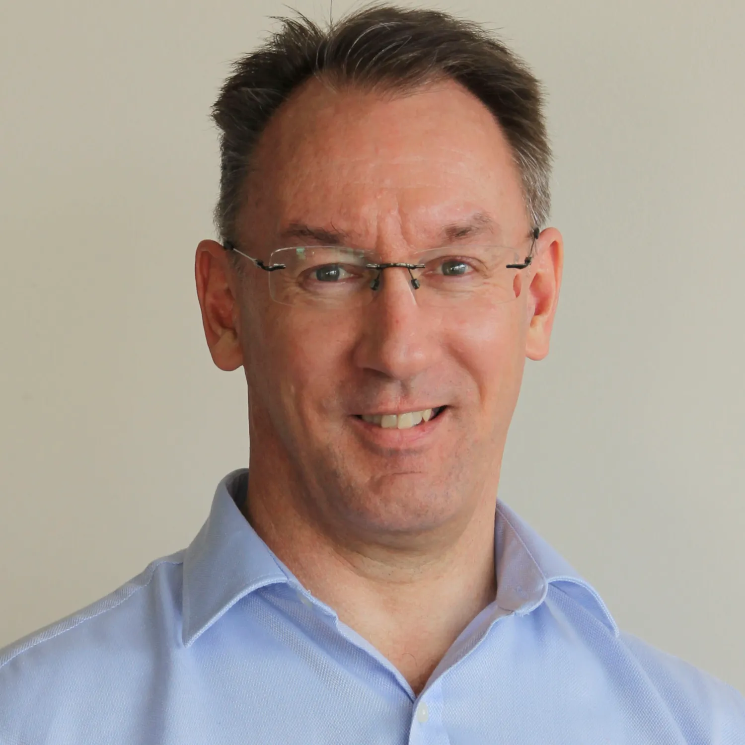 Middle-aged professional in blue shirt and glasses smiling warmly