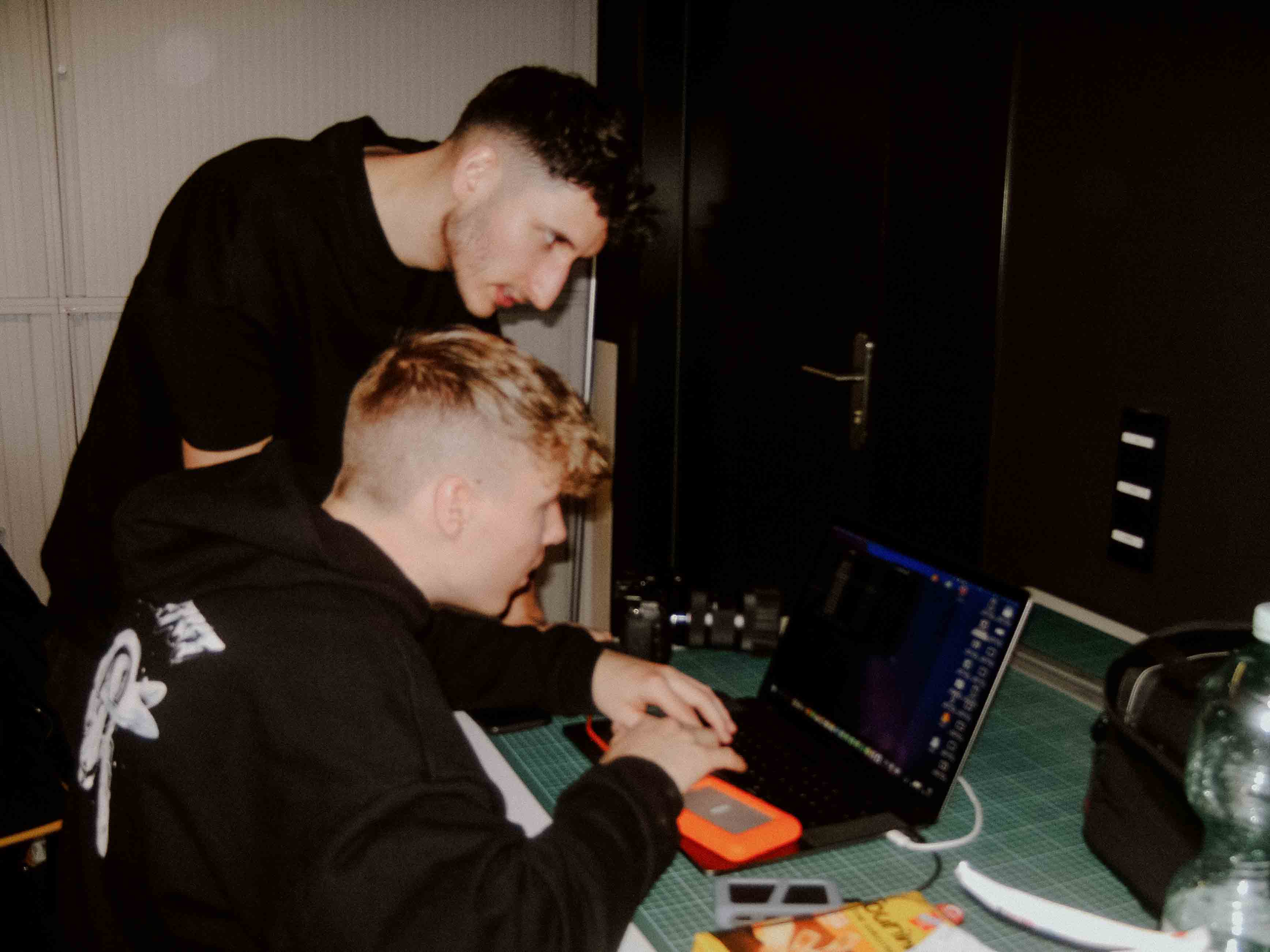 Zwei Filmemacher am Set schauen auf ein Macbook