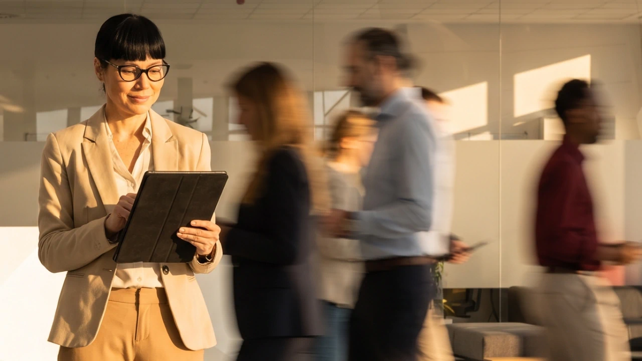Confident workplace manager checking a checklist while professionals walk behind her