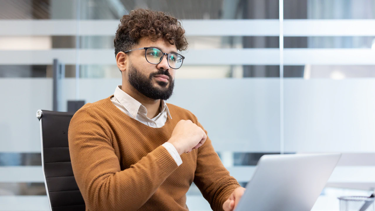Professional sitting at table with laptop looking pensive
