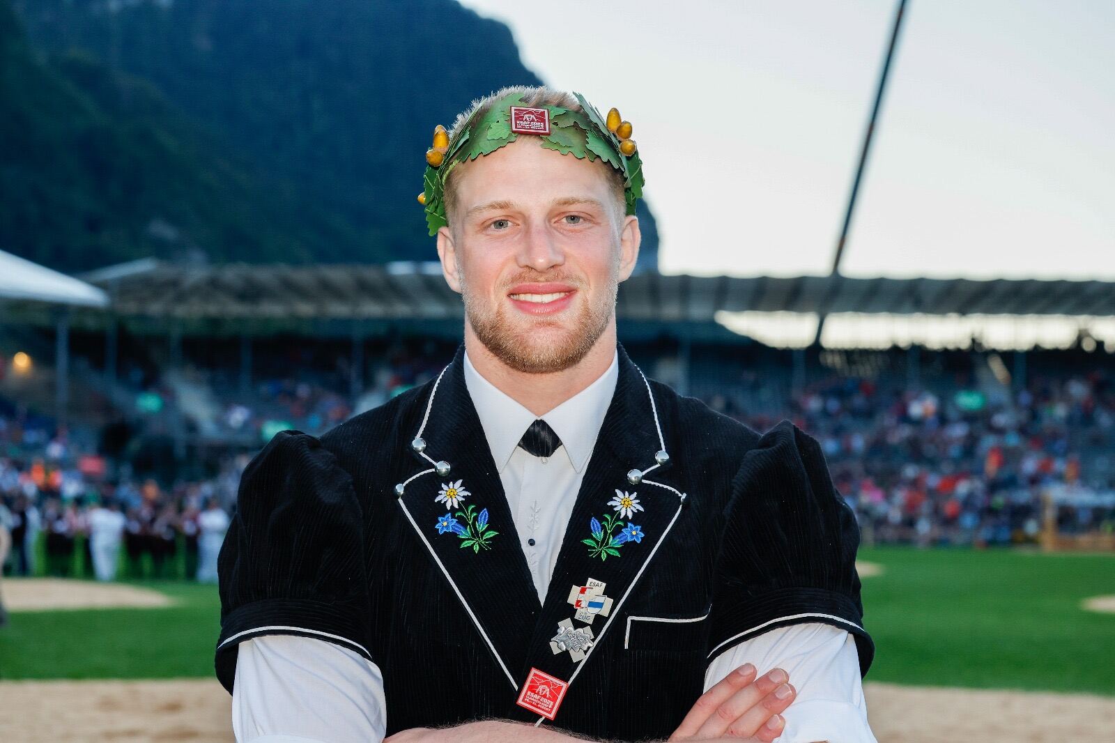 Michael Ledermann in Tracht und mit Kranz vor der Schwingarena