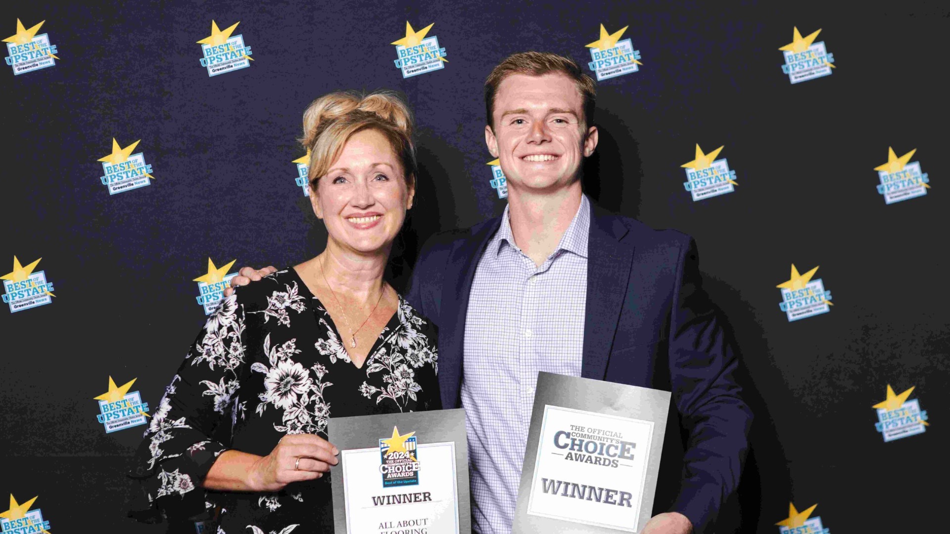 All About Flooring owners holding 2024 Choice Awards winner certificates in front of a Best of the Upstate backdrop.