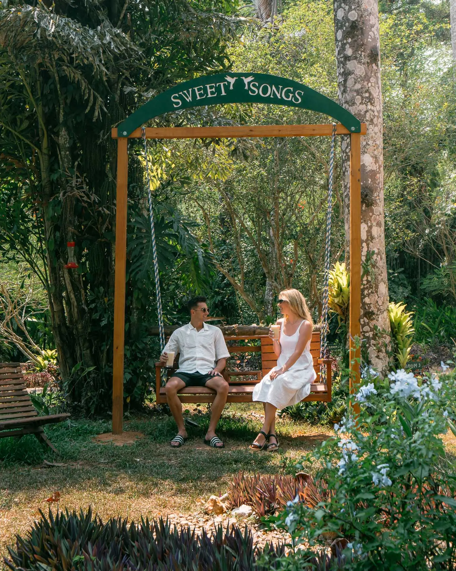Couple relaxing on the Sweet Songs swing at Sweet Songs Jungle Lodge in Belize in a tropical garden setting.
