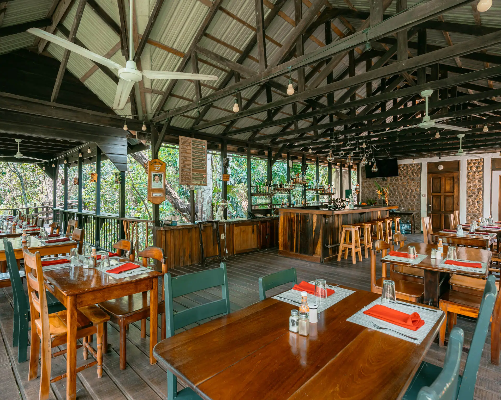 Open-air restaurant and treehouse bar at Sweet Songs Jungle Lodge in Belize with wooden tables and jungle views.