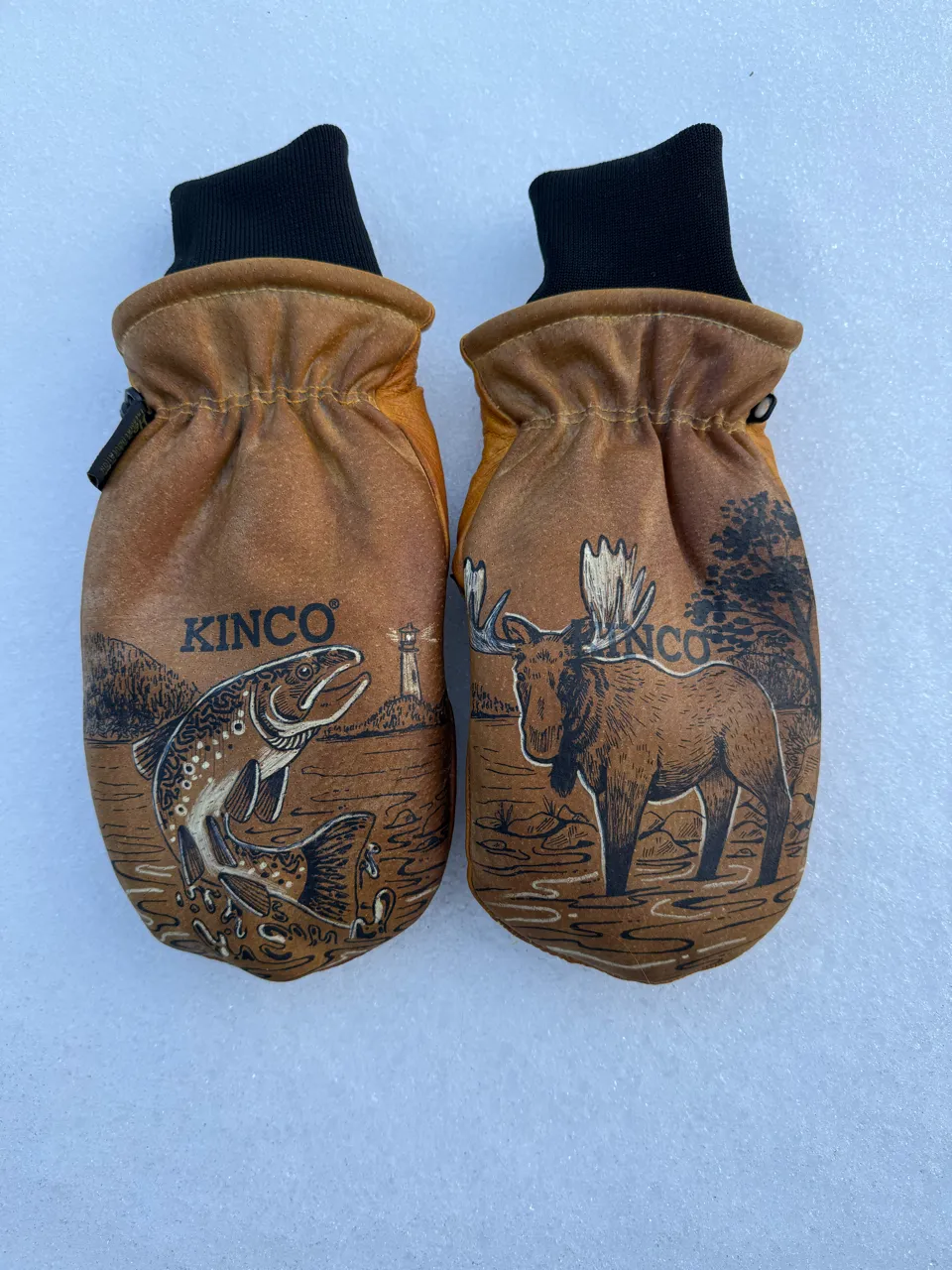 Pair of brown leather mittens with Kinco branding, featuring a fish and a moose illustration on each mitten.