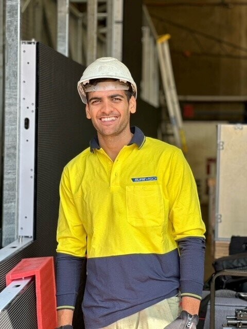 SureVision crew member in hi-vis and hard hat beside LED panels