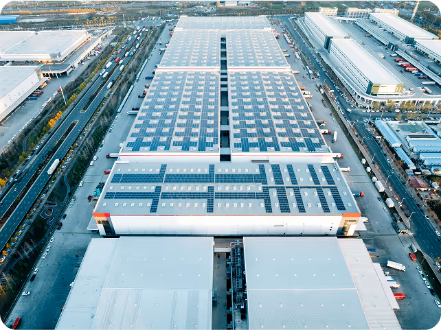 Aerial view of a large industrial complex with rooftop solar panels representing renewable energy generation