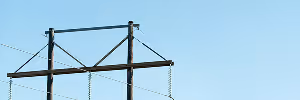 A close-up of a powerline structure against a clear blue sky with a few clouds