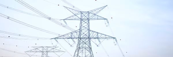 High-voltage electrical transmission towers and power lines against cloudy sky