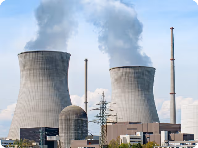 Nuclear or coal power plant with two large cooling towers emitting steam and tall smokestacks