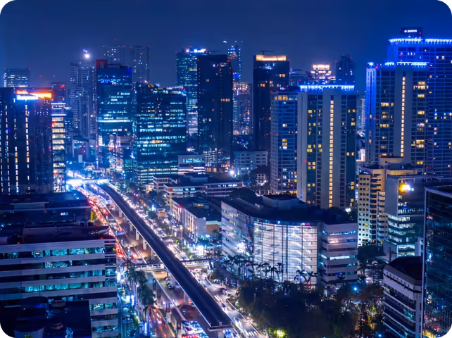 Urban cityscape at night with illuminated skyscrapers and street traffic along main thoroughfare