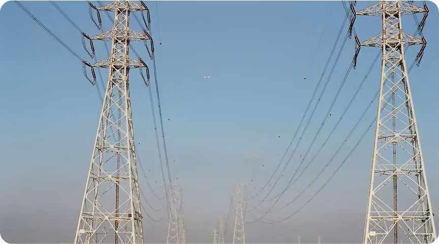Multiple high-voltage transmission towers with power lines extending into hazy distance