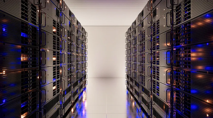 A corridor between two rows of black server racks with blue and orange lights reflecting on the floor.