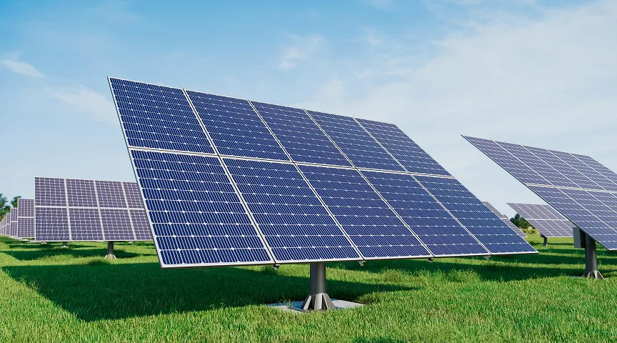 Rows of solar panels angled on green grass under a partly cloudy sky.