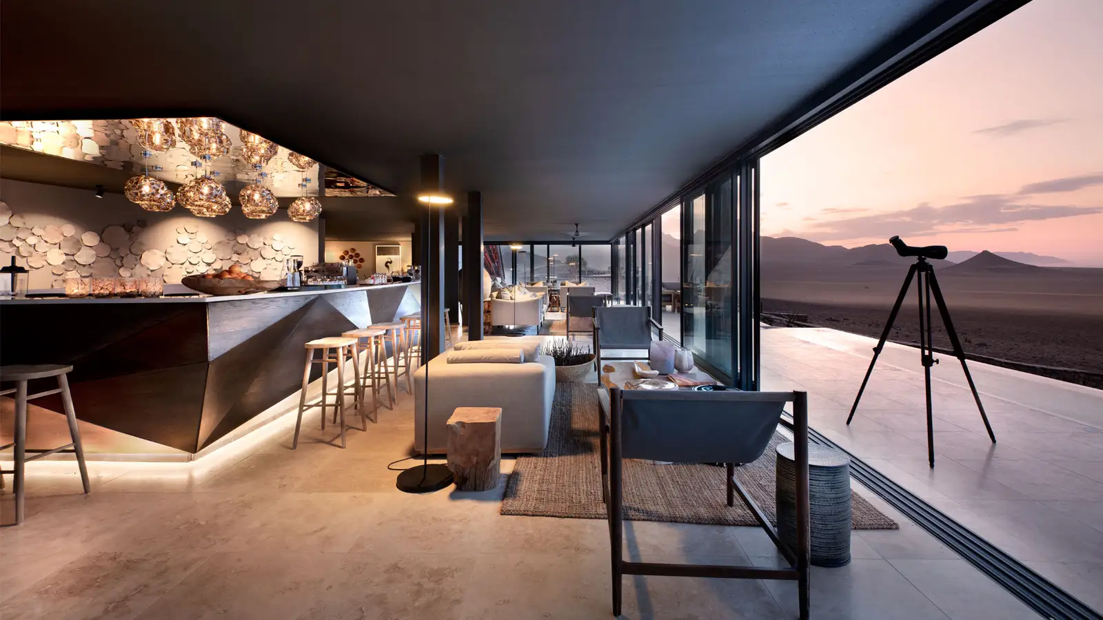 A luxury lounge with a telescope on the deck overlooking the desert at sunset