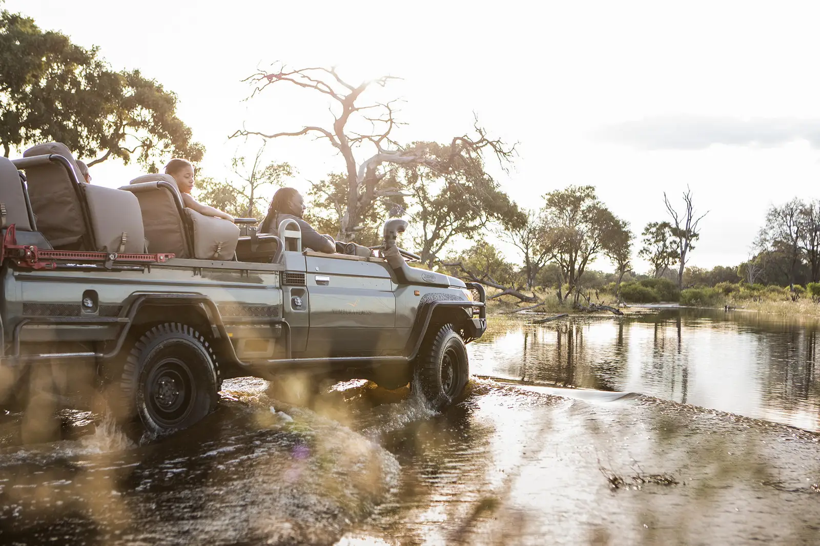 A safari vehicle splashes through shallow water in a prime game-viewing area