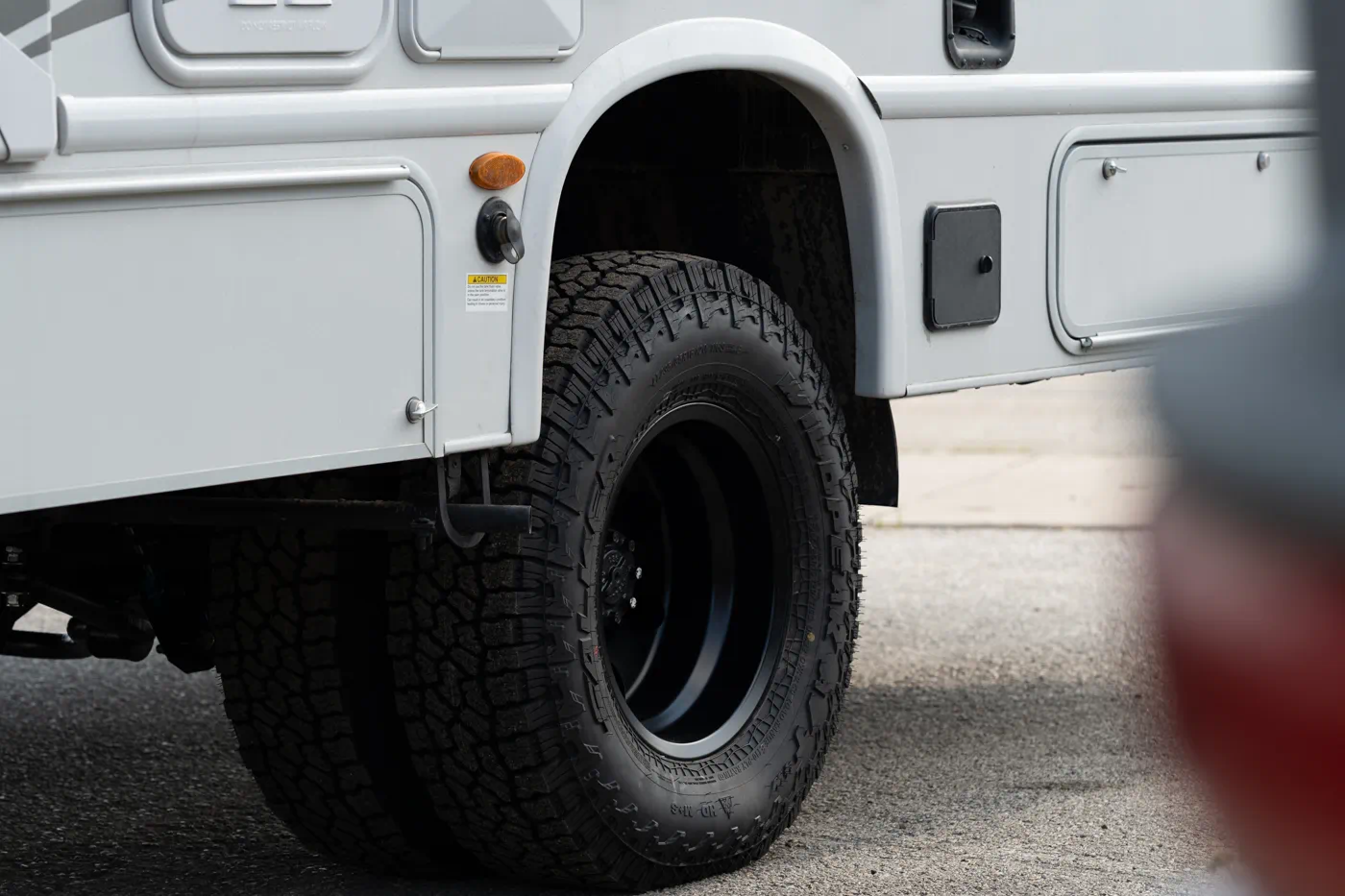 Close-up of aggressive all-terrain tire and black wheel on 2025 Thor Outlaw Class C motorhome after WeldTec 6" Off Grid lift kit installation at Adrenaline Offroad Co. Houston TX