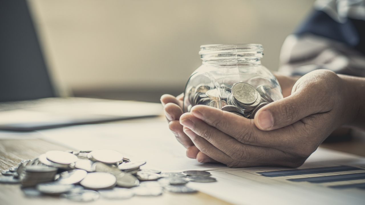 CNA holding a jar of money
