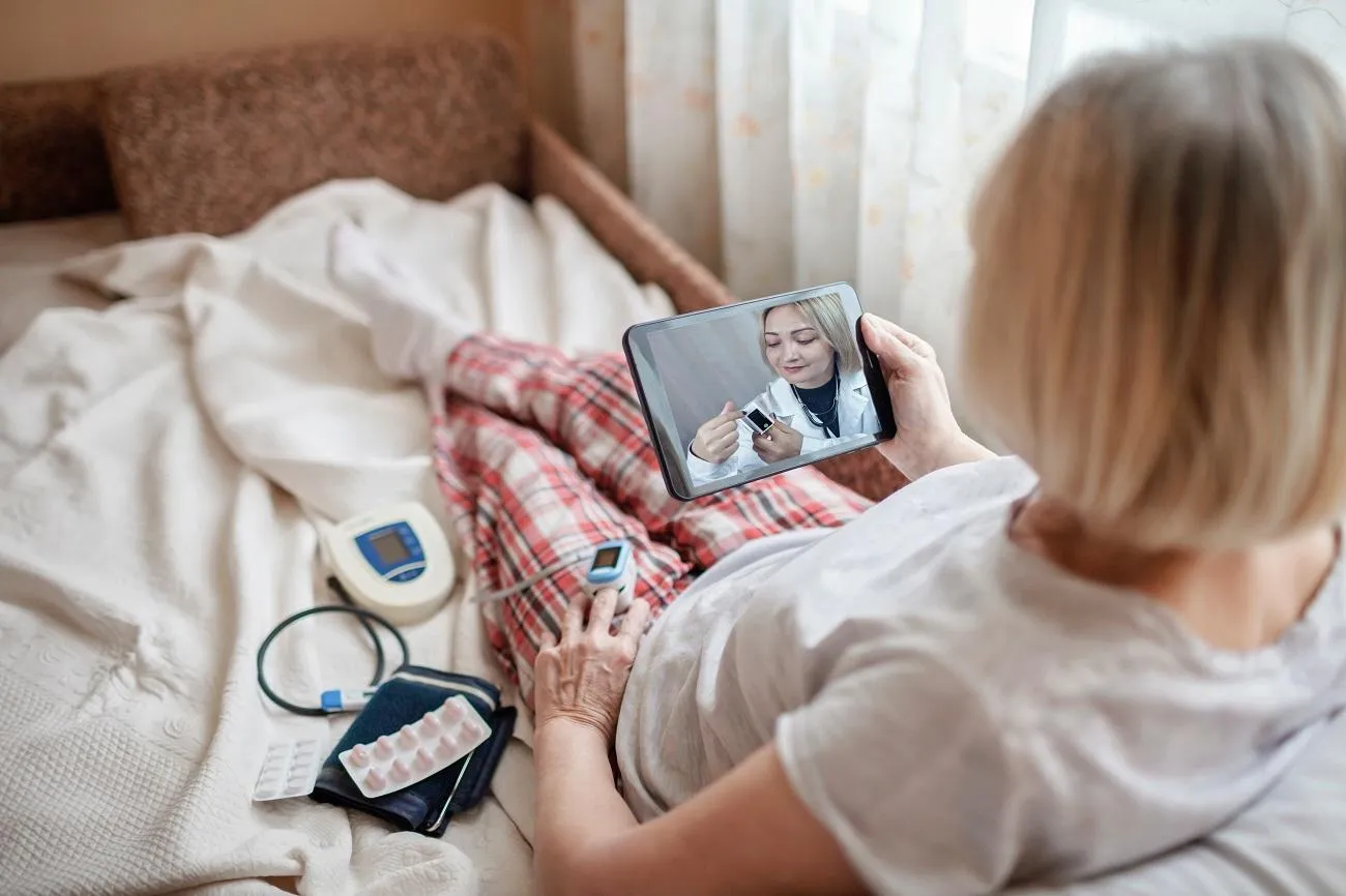 Patient and caregiver using digital technology for remote monitoring at home.