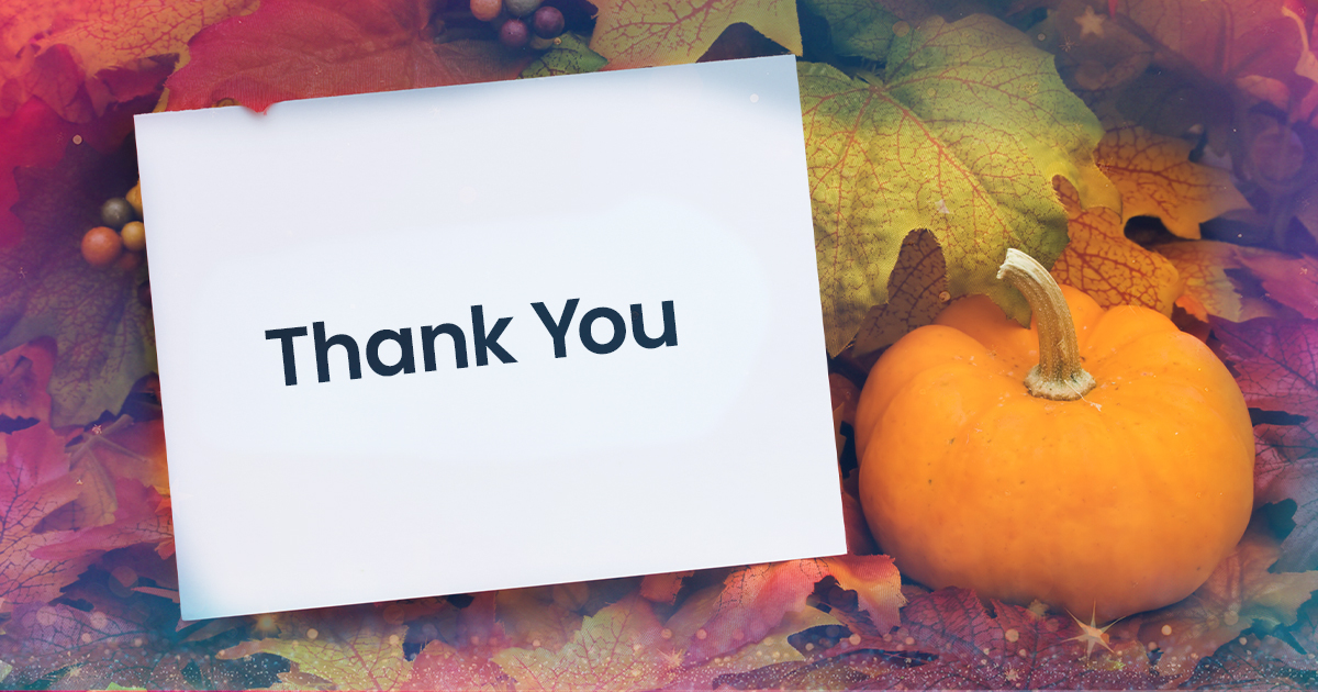 A 'Thank You' card laid among pumpkins and fall leaves.