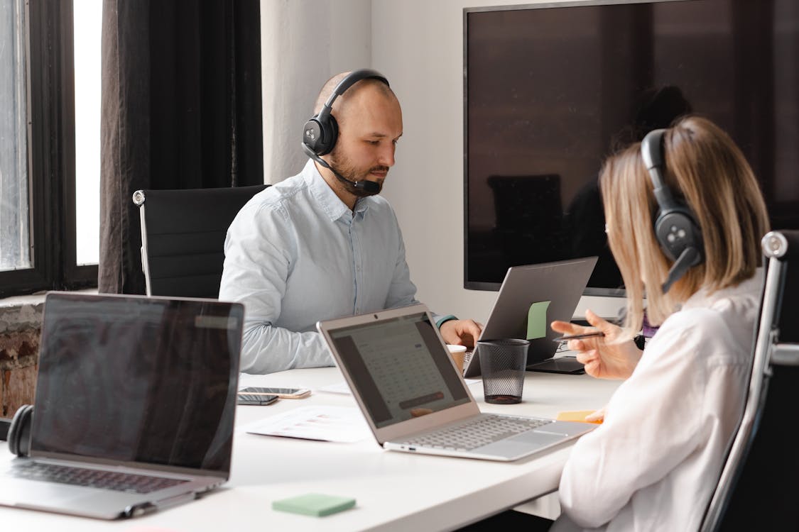 Customer support agents working together with laptops and headsets in an office setting