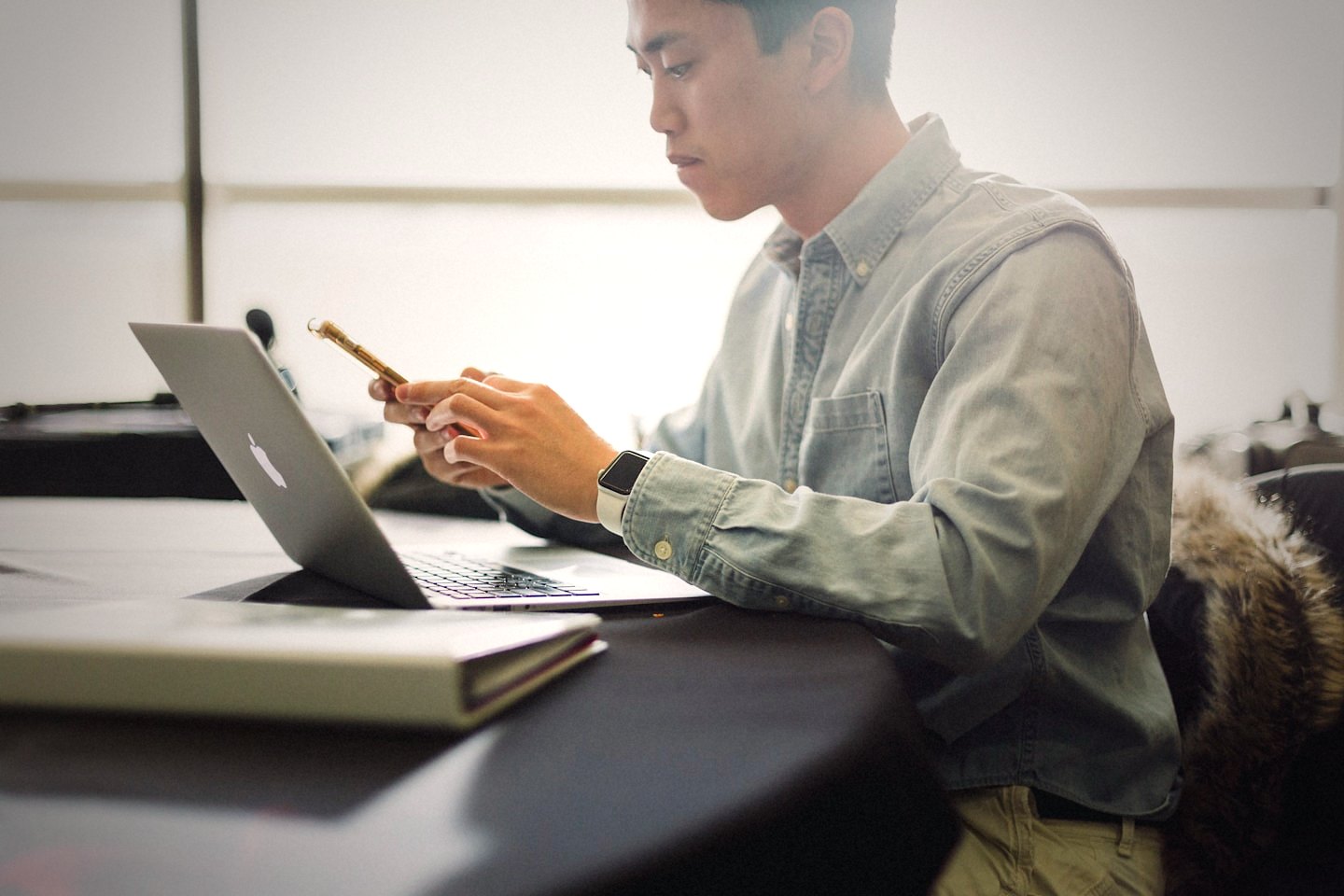 Someone checking their phone beside a laptop