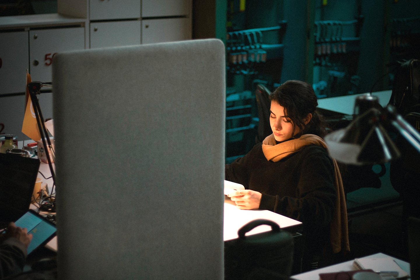 A person working late at a desk under a warm lamp