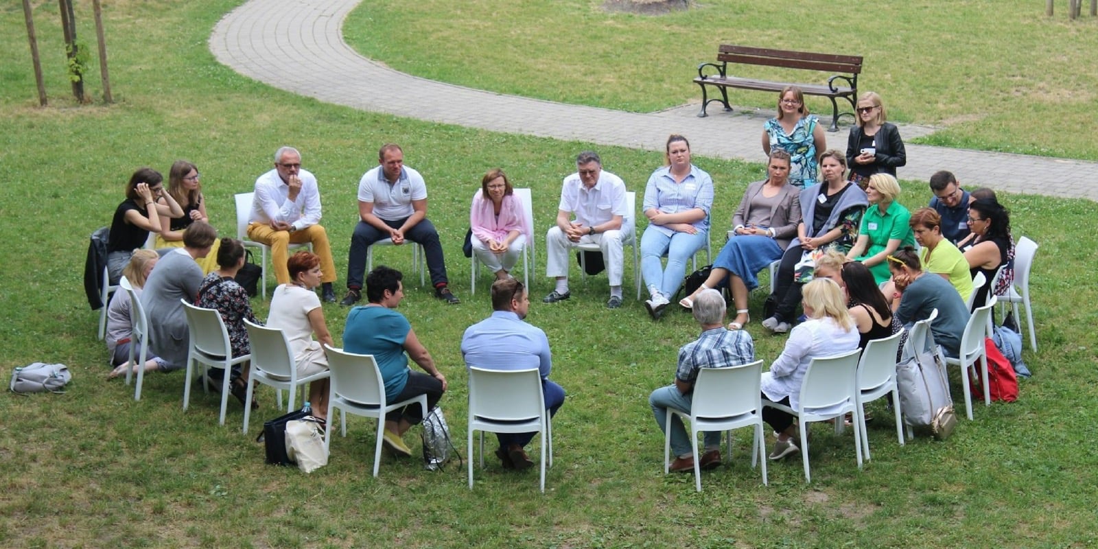 A circle of people sitting and talking together outdoors