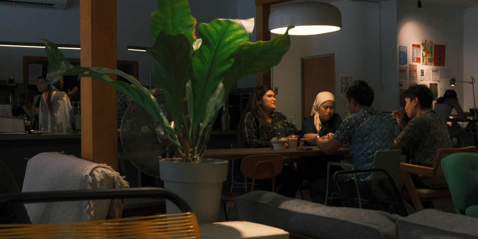 A group of people in conversation around a table in a cafe