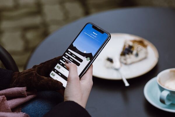 A person using a community app on their phone at a cafe table
