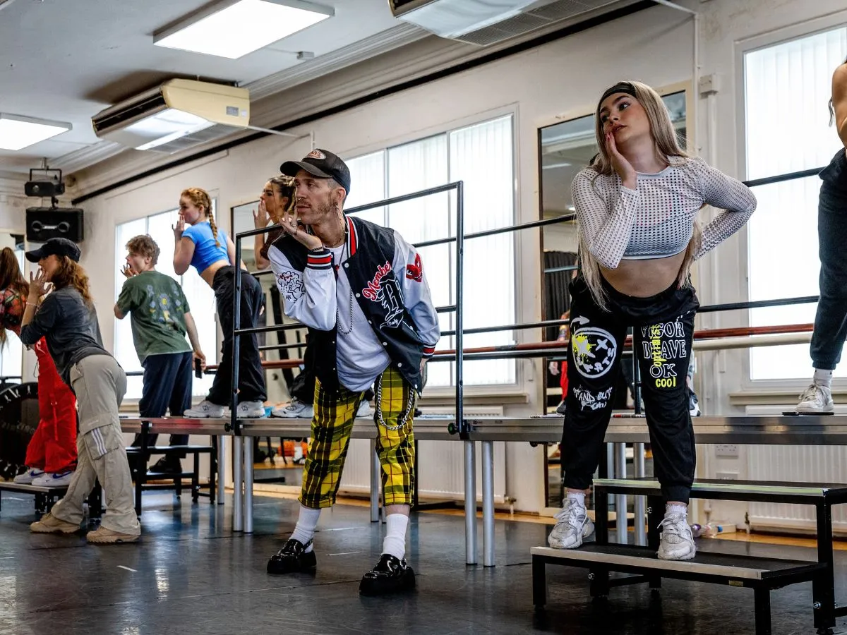 Students in a rehearsal studio holding expressive poses in character during a group session.