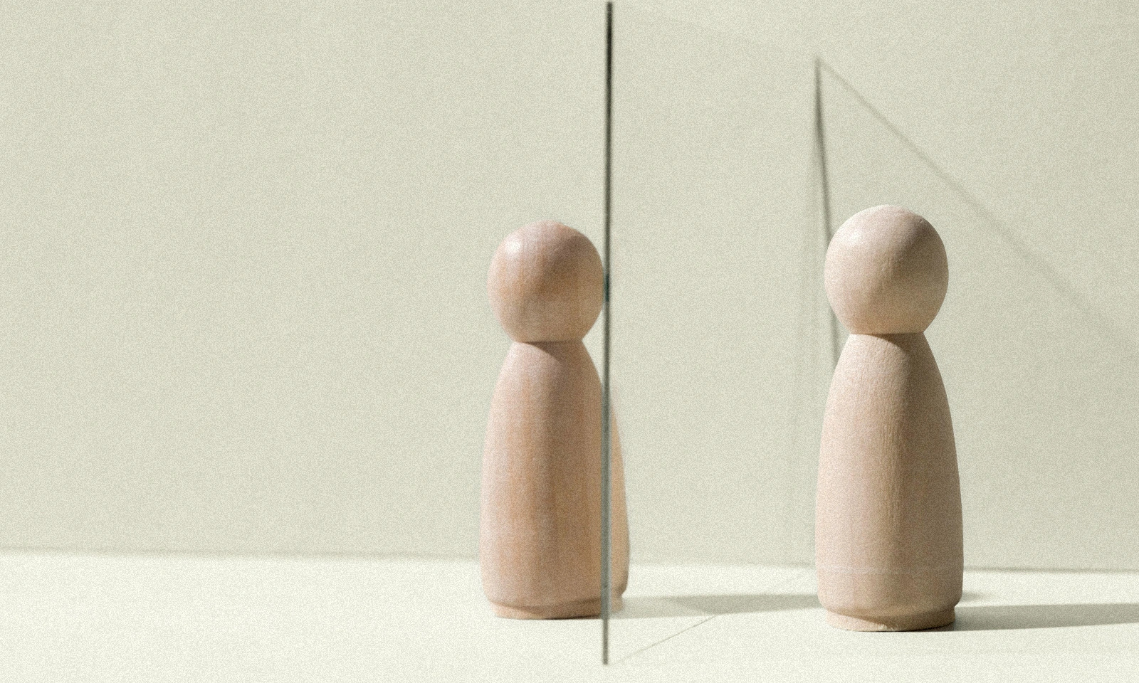 Wooden toy dolls separated by a glass wall