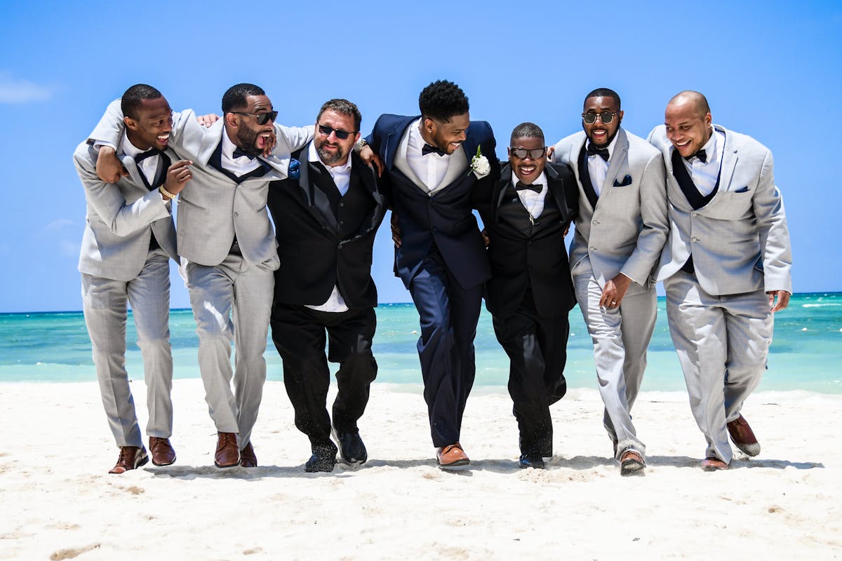 A bunch of men in suits on the beach for a wedding