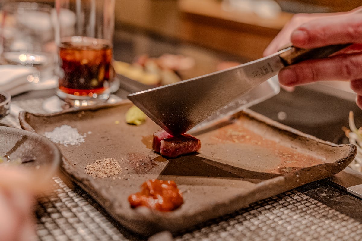 A private chef cutting a piece of meat on a cutting board with a butcher's knife