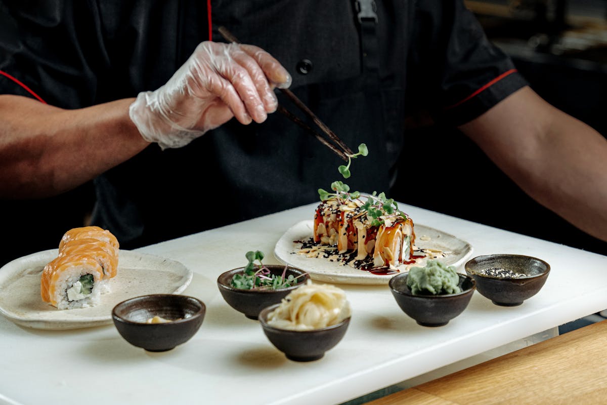 A chef placing sauce over food created for a client