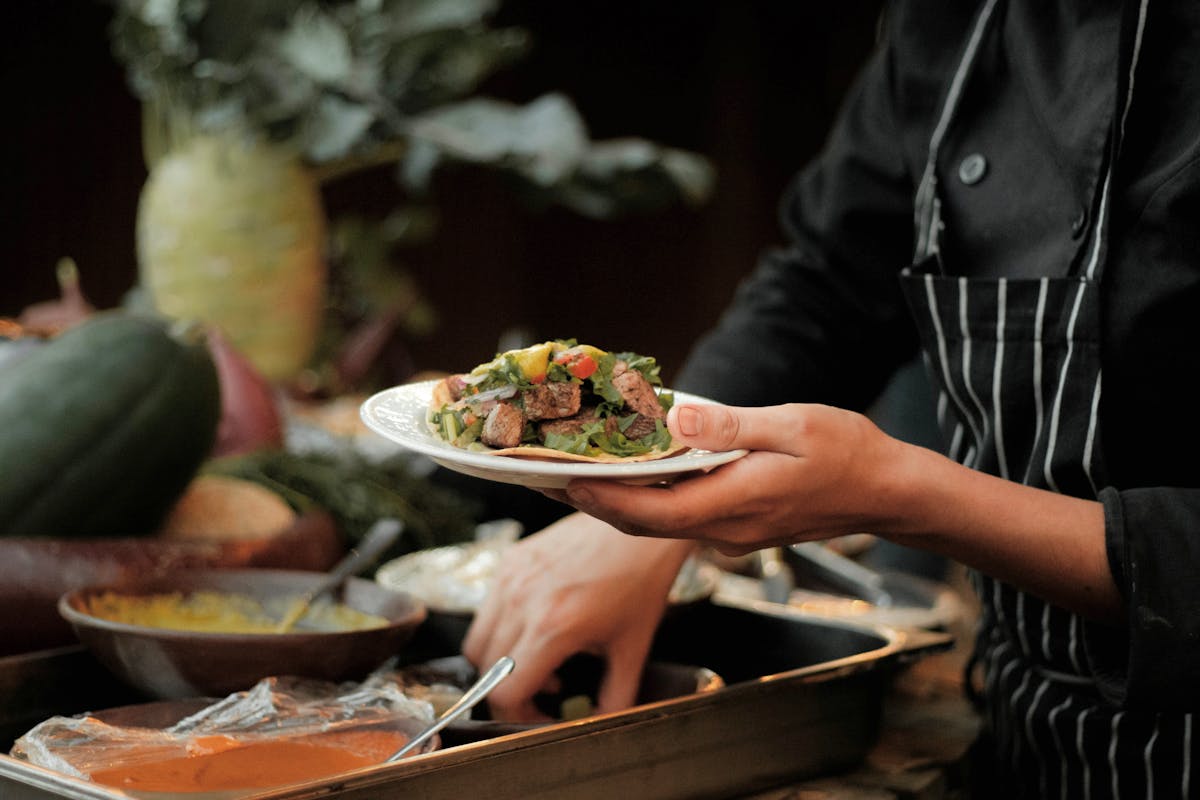 A private chef holding a bunch of plates of food for clients
