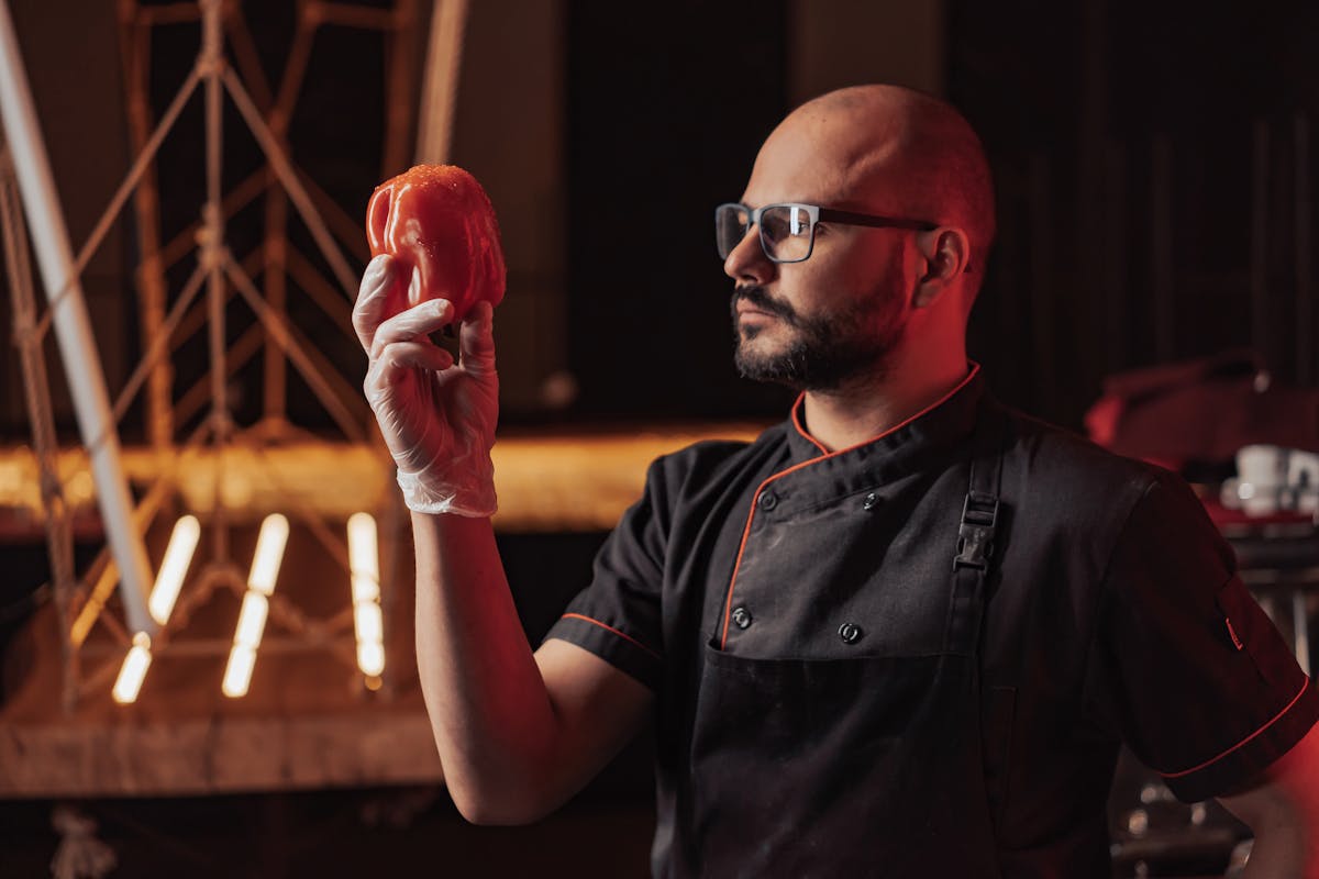A chef looking at a pepper to make sure it is good